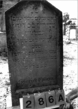 Grabstein 286 (Index: 99797820) Material: Sandstein, weiß Zustand: stark verwittert Maße HxBxT: 96x44x10 cm Beschreibung: Stele, giebelartiger Abschluß oben abgeflacht, Sockel: Grabstein 286A