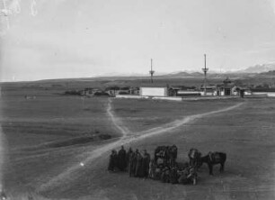Gruppenportrait : Portrait einer Gruppe aus Zentralasien mit Reittieren vor einem Gebäudekomplex, vermutlich ein Kloster im Tian Shan Hochgebirge