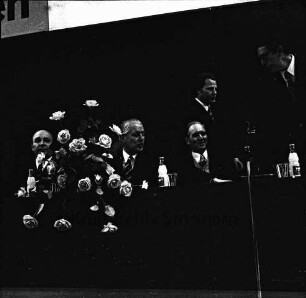 CDU: Wahlveranstaltung zur Landtagswahl 1974: Stormarnhalle Bad Oldesloe: N.N., Ministerpräsident Gerhard Stoltenberg, Landesminister für Soziales Karl Eduard Claussen und weitere Teilnehmer auf dem Podium: vorn links Blumenschmuck, rechts Mikrofon: 10. März 1974