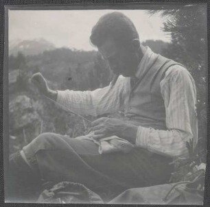 Wilhelm Paulcke mit Zigarre beim Stopfen seiner Kleidung