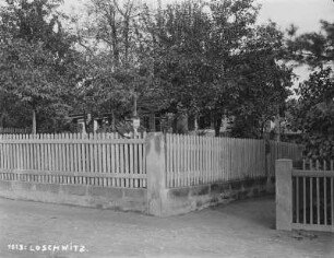 Dresden, Blick auf ein Wohnhaus in einem Garten, umgeben von einem hölzernen Staketenzaun über den ein Junge schaut