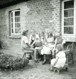 Arbeitsmaid des Reichsarbeitsdienstes bei Handarbeit und Kinderbetreung