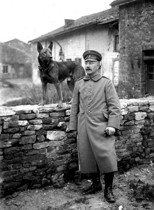 Erster Weltkrieg : Deutscher Soldat vor einer Mauer, darauf ein Schäferhund
