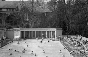 Schwimmbad : Badende im Thermalschwimmbad Badenweiler. Am Beckenrand sonnen sich Menschen.