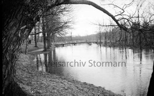 Beste: Kurpark: Hochwasser: hinten Mitte Fußgängerbrücke: darauf zwei Jungen: hinten links Personen im Park: hinten rechts Wohnblocks am Meisenweg hinter Bäumen