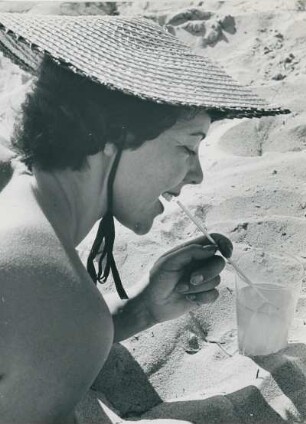 Model Helga am Strand der Ostsee. Ein kühler Drink tut bei der Hitze gut.