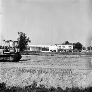 Autohaus Homburg: Hammoorer Weg, Ecke Lohe: in Bau: teilweise noch mit Gerüst: hinten rechts Firmengebäude in Bau, Baukran: vorne Planieren eines Baugrundes, Planierraupe