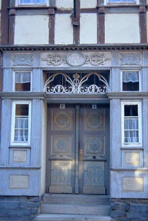 zweiflüglige, zurückgebaute Eingangstür; reichhaltige Verzierungen