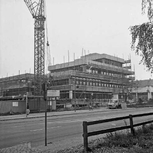 Gemeindeverwaltung: Rathaus: Hauptstraße: Neubau vor Fertigstellung mit Gerüsten: davor Fußgänger und Fahrradfahrer: rechts Bauwagen: links Kran: im Vordergrund rechts Zaun: rechts oben Baumäste
