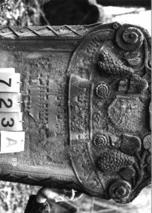 Grabstein 723 (Index: 99751661) Material: Sandstein Zustand: abgeblätt/verwitt/großer Textverlust Maße HxBxT: 125x71x14 cm Beschreibung: Stele, in Voluten auslaufender Rundbogenabschluß Symbolik: Trauben, Blätter, Blüten, Muschel, Wappenschild, Schriftband, Voluten, Rauten: Grabstein 723A