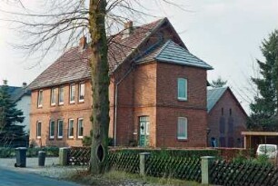 Tremsbütteler Weg 21-23: traufständiges Doppelwohnhaus aus Backstein mit umlaufendem Gesims: Straßenfront: östliche Giebelseite mit Eingangsanbau: dahinter rechts Wirtschaftsgebäude