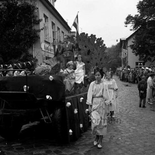 Karpfenfest: Umzug: Matthias-Claudius-Straße / Ahrensböker Straße (hinten): Festwagen, mit Kindern, winkendem Prinzen, Korallenthron, Fisch, begleitet von Mädchen als Sternen: links Fassade mit Ladenschild "Kolonialwaren", Zuschauer, Fahnenschmuck, Wimpelgirlande: hinten rechts "Hotel Stadt Hamburg", Einmündung Paul-von-Schoenaich-Straße, Zuschauer, 8. Oktober 1961