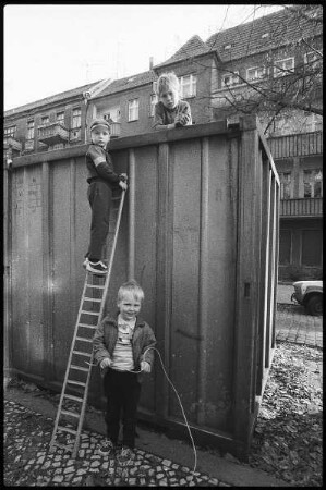 Drei Jungen am Container mit Leiter