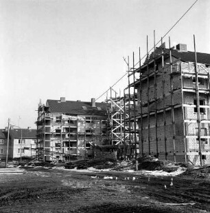 Wohnungsbau: Kellerberg-Süd: zwei mehrgeschossige Wohnblocks im Rohbau mit Gerüsten: davor Zufahrtsweg, Sand- und Erdhaufen sowie Baumaterial: hinten links zwei Wohnblocks nach Fertigstellung