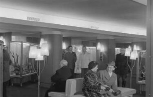 Messegäste in einem Foyer mit Stehlampen und Schauvitrinen