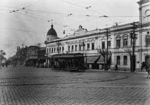 Alltagsszene mit Straßenbahn : Eine belebte Straße mit einer Straßenbahn und zahlreichen Passanten.