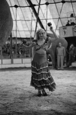 Eine Artistin mit Maracas in den Händen bei einem Auftritt vor Publikum in der Manege des Volkseigenen Circus Aeros