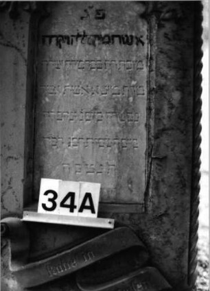 Grabstein 34 (Index: 100092760) Material: Sandstein Zustand: Schrift auf Sockel verwittert Maße HxBxT: 163x65x30 cm Beschreibung: Stele auf Sockel, Schriftfelder auf Stele und Sockel Symbolik: Blumenornamente, Schriftband: Grabstein 34A