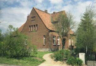 Pöls: Dorfstraße 36: ehemalige Schule: giebelständiges Backsteingebäude: Straßenfront: Traufseite mit Eingangsportal und Zwerchhaus: hinten links Querbau
