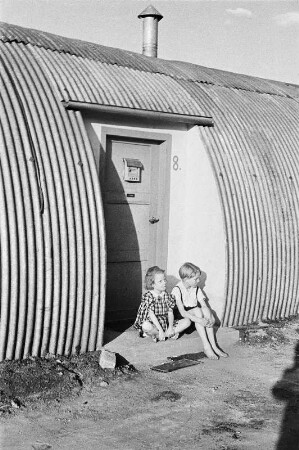 Berlin. Nissen-Hütten (1945/1948) am S-Bahnhof Hohenzollerndamm. Zwei vor der Tür von Haus Nr. 8 sitzende Kinder