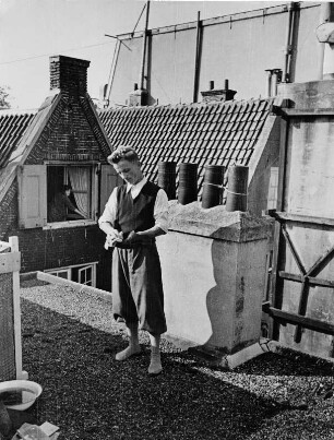 Niederlande. Amsterdam. Daddel (Kurt Feige) auf dem Dach eines Hauses in der Prinsengracht. Er putzt Schuhe
