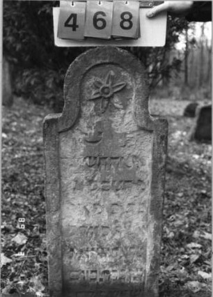 Grabstein 468 (Index: 99752854) Material: Sandstein Zustand: stark verwittert mit großem Textverlust Maße HxBxT: 67x41x9 cm Beschreibung: Stele, eingezogener Rundbogenabschluß, Schriftfeld eingetieft Symbolik: Blüte: Grabstein 468