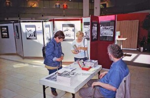 Sparkasse Holstein: Hauptstelle in der Hagenstraße: Halle im Erdgeschoss: Besucher am Bücherstand zur Kindervogelschießenausstellung des Kreisarchivs, Archivmitarbeiter Manfred Holzgreve am Tisch sitzend