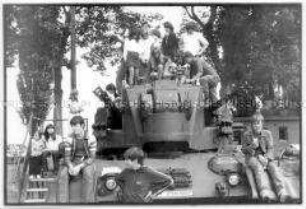 Kinder sitzen auf einem Panzer (Altersgruppe 18-21)