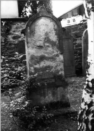 Grabstein 88 (Index: 100094788) Material: Sandstein Zustand: völlig verwittert Maße HxBxT: 169x73x22 cm Beschreibung: St, getreppt. Sock, Rundbogenabschl. m. Mittelakroter, Schriftfeld eingetieft: Grabstein 88