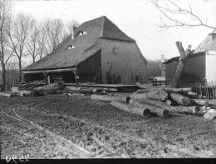 Blick auf die Steinmühle. rechte Bildseite: Stapel Baumstämme