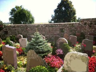 Kirchhof im Osten mit Kirchhofmauer (Wehrgang im 18 Jh abgetragen) mit erhaltenen Schießscharten in Brusthöhe in übersichtlichem Verlauf