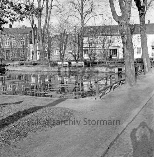 Feuerlöschteich ("Pansenteich"): hinten Rathausstraße, Ecke zu rechts Mittelweg: umgeben von Grünanlage mit Parkbänken, Bäume, Holzgeländer: hinten links Gasthaus Jägerstube, rechts daneben Schlachterei Wunder: unten rechts Schatten des Fotografen