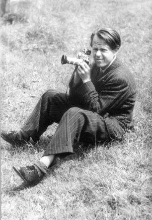 Roger Rössing mit Kamera auf einer Wiese sitzend