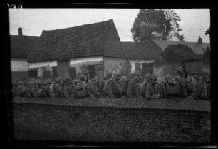 Metz-en-Couture (Dep. Pas-de-Calais, Frankreich): Soldaten mit Marschgepäck hinter einer Steinmauer (Rückansicht)