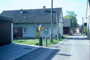 Dorstraße mit Häusern, links kleines Taubenhaus