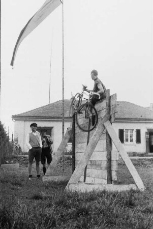 Arbeitersportler beim Überwinden einer Eskaladierwand mit Fahrrad