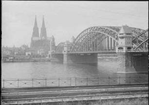 Köln, Hohenzollernbrücke : Köln. Eisenbahn- und Straßenbrücke (Hohenzollernbrücke) über den Rhein (1907-1911, F. Beermann, F. Dircksen; Steinbau u. Türme, F. Schwechten). Teilansicht (oberstrom) mit Dom vom rechten Ufer