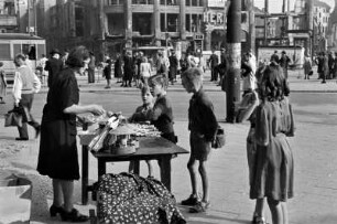Berlin, Alexanderplatz. Frau an einem Verkaufstisch mit Spielzeug. Im Hintergrund das zerstörte Hertie-Kaufhaus