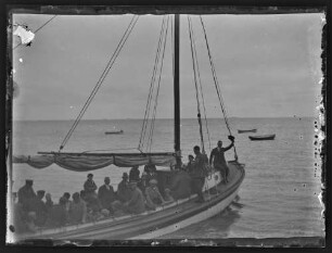 Segelboot mit mehreren Personen an Bord auf Meer oder großem See
