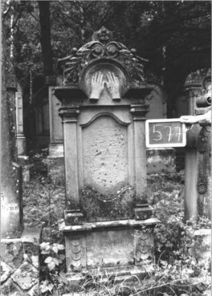Grabstein 577 (Index: 99895385) Material: Sandstein Zustand: leicht verwittert; Schriftplatte fehlt Maße HxBxT: 176x58x25 cm Beschreibung: Stele mit eingezogenem Rundbogenabschluss und Pilastern; Sockel Symbolik: Priesterhände, Zweige: Grabstein 577