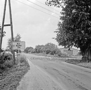 Straße Richtung Bargfeld-Stegen nach Ausbau: links Ortsausgangsschild: dahinter Strommast: rechts Baum: dahinter Wirtschaftsgebäude