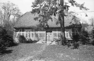 Kneeden: Forsthaus: davor Sandhaufen: links am Haus auf Bank zwei Personen: links und rechts Büsche: rechts großer Baum: hinten weitere Bäume