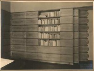 Landhaus Dr. Schneider Inneneinrichtung: Schlafzimmer mit holzvertäfelter Wand darin integrierte Zimmertür, Schrank und Bücherregal