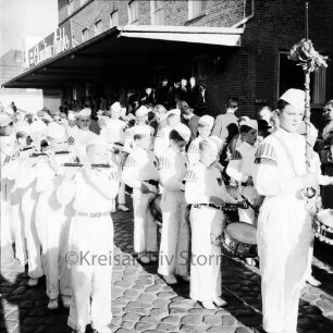 Karpfenfest: Umzug: Spielmannszug in Aufstellung, spielt vor Claudius-Mühle: dahinter Zuschauer am Straßenrand und auf Laderampe der Mühle (mit Firmenschild), 11. Oktober 1959