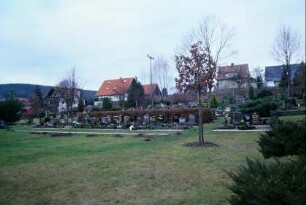 Blick auf die Gräber des Friedhofes; im Hintergrund Häuser