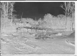 Staustufe Schweinfurt. Straßenbrücke. Transportsteg zur umspundeten Baugrube des Pfeilers 4 im Saumain. Im Vordergrund die Verkleidsteine für den Pfeiler. Schweinfurter Pegel = 95 cm.