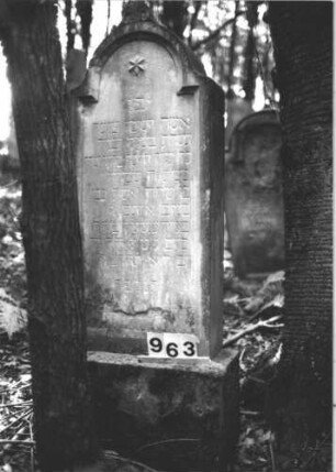 Grabstein 963 (Index: 99899495) Material: Sandstein Zustand: unten verwittert, sonst etwas angewittert Maße HxBxT: 155x63x34 cm Beschreibung: aufgesockelte Stele mit eingezogenem Rundbogenabschlss, im Bogenfeld Stern Symbolik: Stern: Grabstein 963