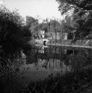 Schlossmühle: davor Mühlenredder, Mühlenbrücke: vorne Schlossgraben mit Spiegelungen: im Vordergrund Uferweg, Busch