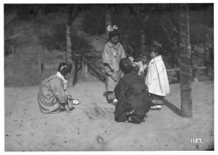 Nara, Japan. Spielende Kinder. Drei Japanerinnen und Kinder spielen mit gezeichneten Kästchen im Sand