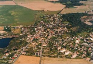 Böhlitz (Kreis Wurzen). Westliche Wohnsiedlungen und Dorfkern (Platzdorf) zwischen Porphyrsteinbruchseen am Spielberg (links) und Holzberg (rechts). Luftbild-Schrägaufnahme von Westen/Südwesten